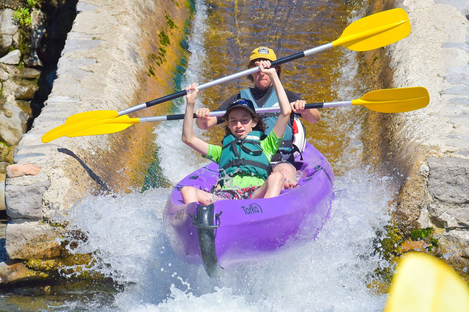 Des enfants passent une glissière en canoë sur l'Ardèche